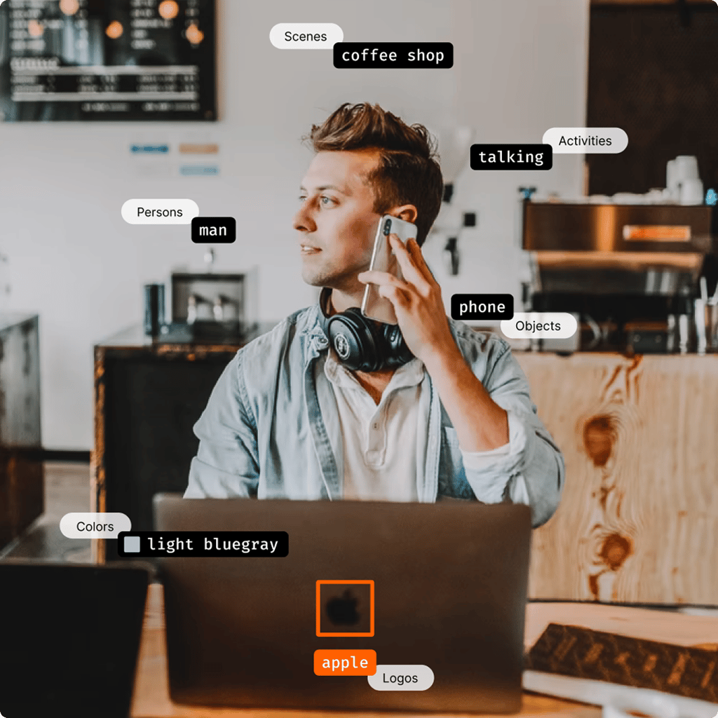 Demonstração de análise de IA do Visual Insights mostrando tags detectadas - homem falando ao telefone em cafeteria com detecção de logotipo da Apple e cor azul acinzentado claro